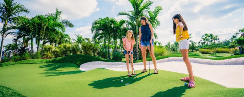 A mom and her daughters enjoy a game of mini golf